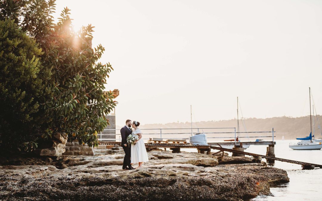Sydney Wedding Photographer - bride and groom stand on beach rocks at sunset