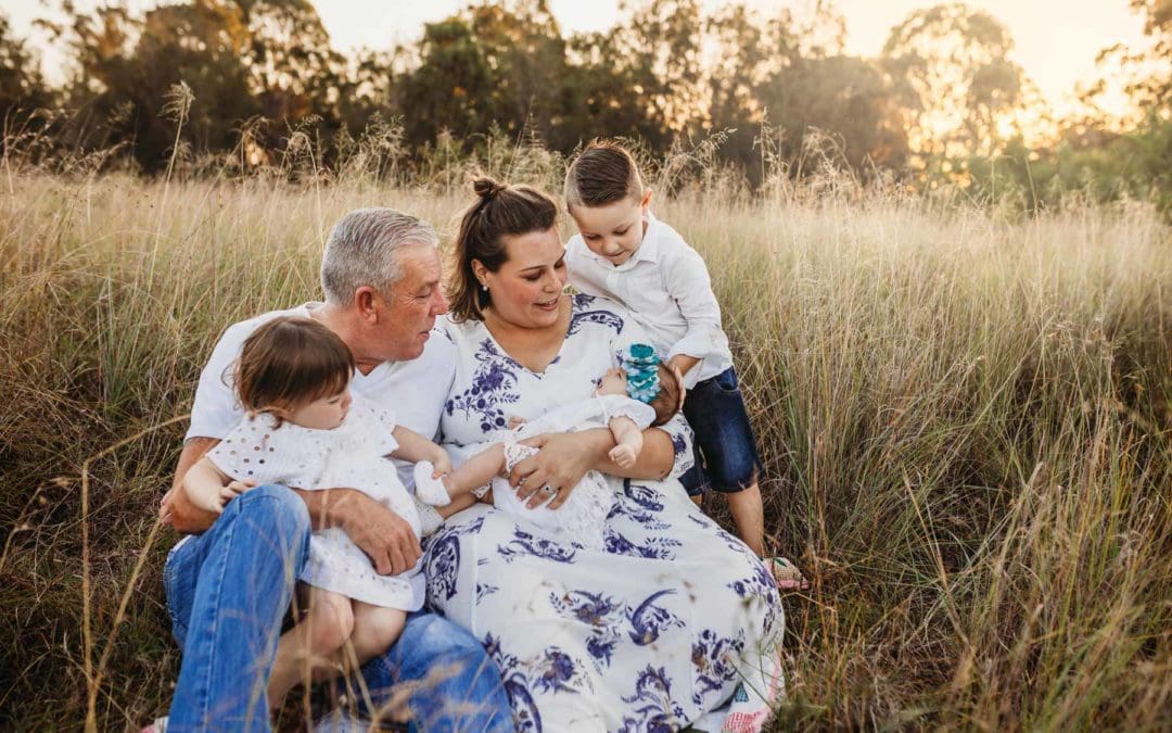 A family sitting in a grass field at sunset