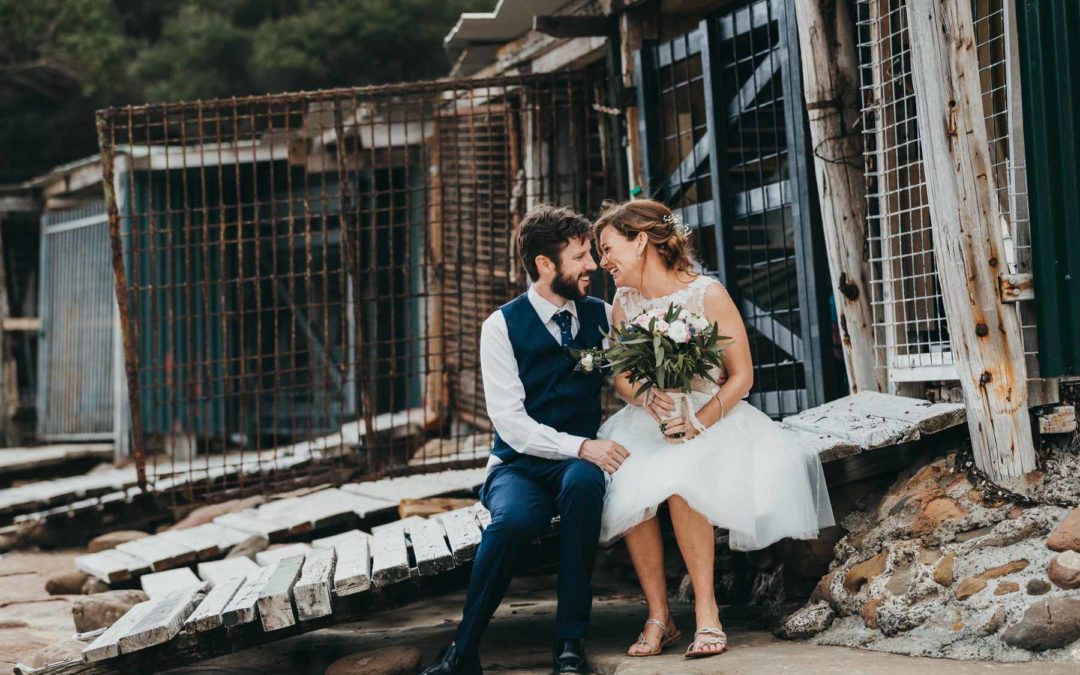 Newlyweds laugh near the Sandon Point boat sheds