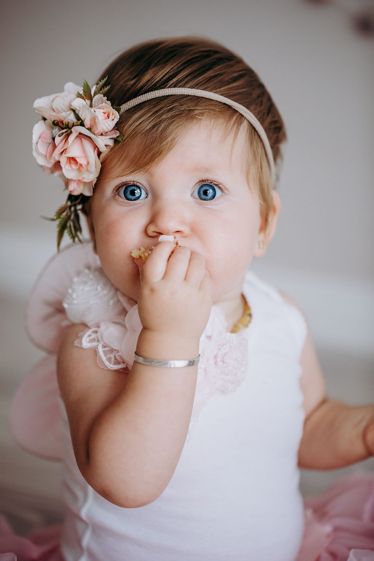 Little girl with blue eyes stuffs cake into her mouth
