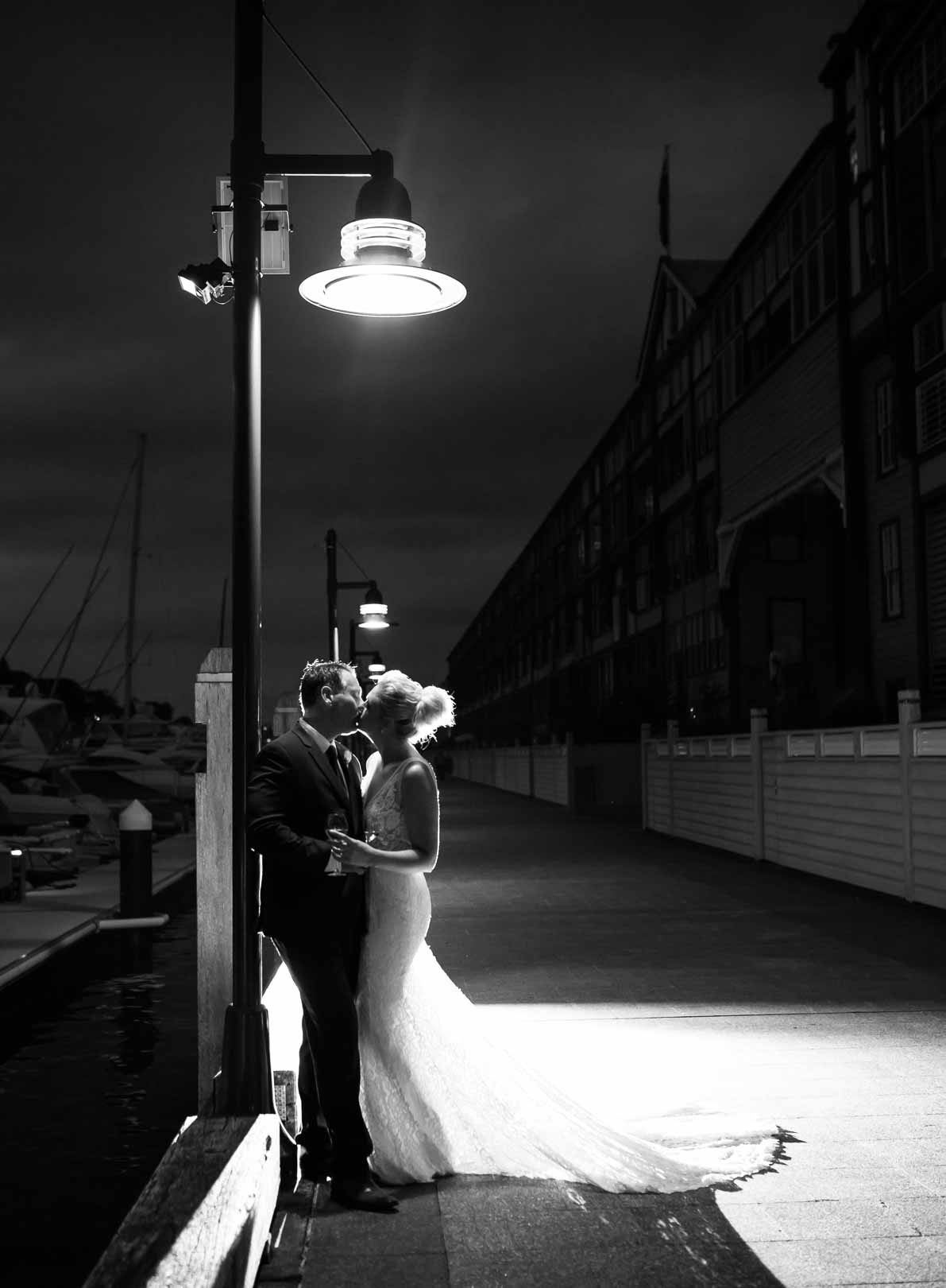 A married couple kiss under a street light at night at Woolloomooloo