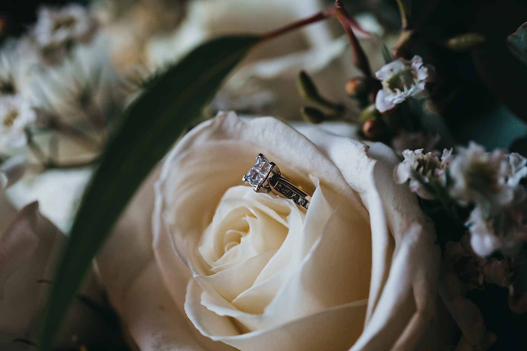 Detail photograph of a brides wedding ring sitting in her wedding bouquet