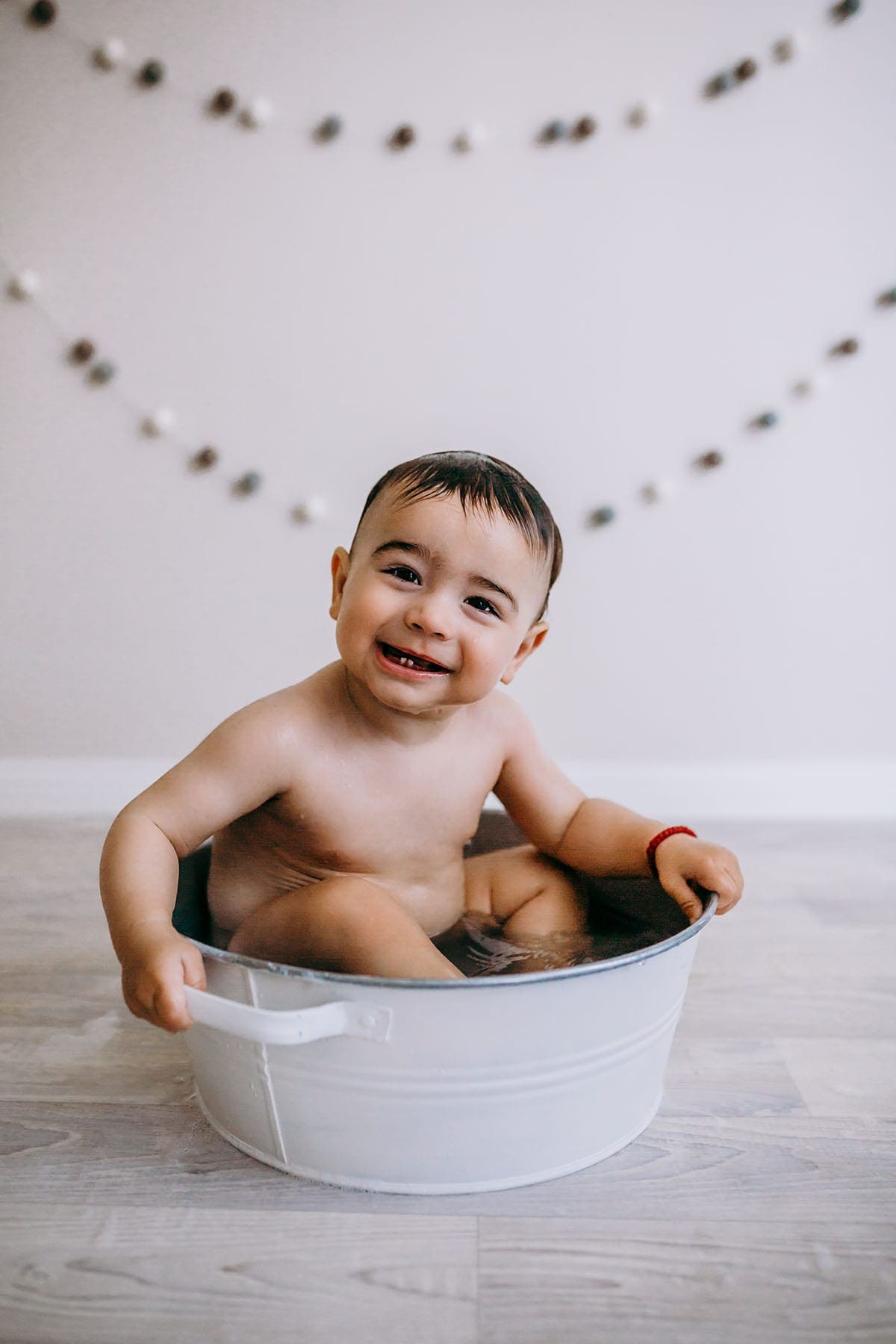 Elysium-Photography-Sydney-Baby-Studio-Photographer-Daniil-46 A baby boy sits in a vintage bath tub with a big grin on his face