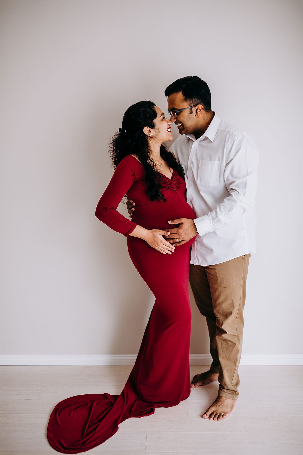 A man cradles his pregnant partners belly as they look lovingly at each other