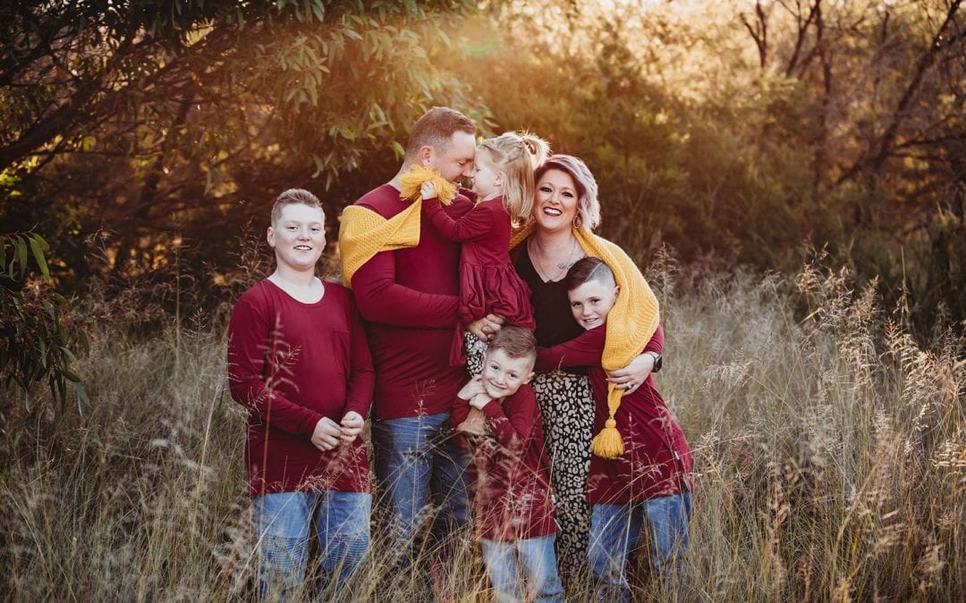 Parents cuddle their 4 children wrapped in a blanket