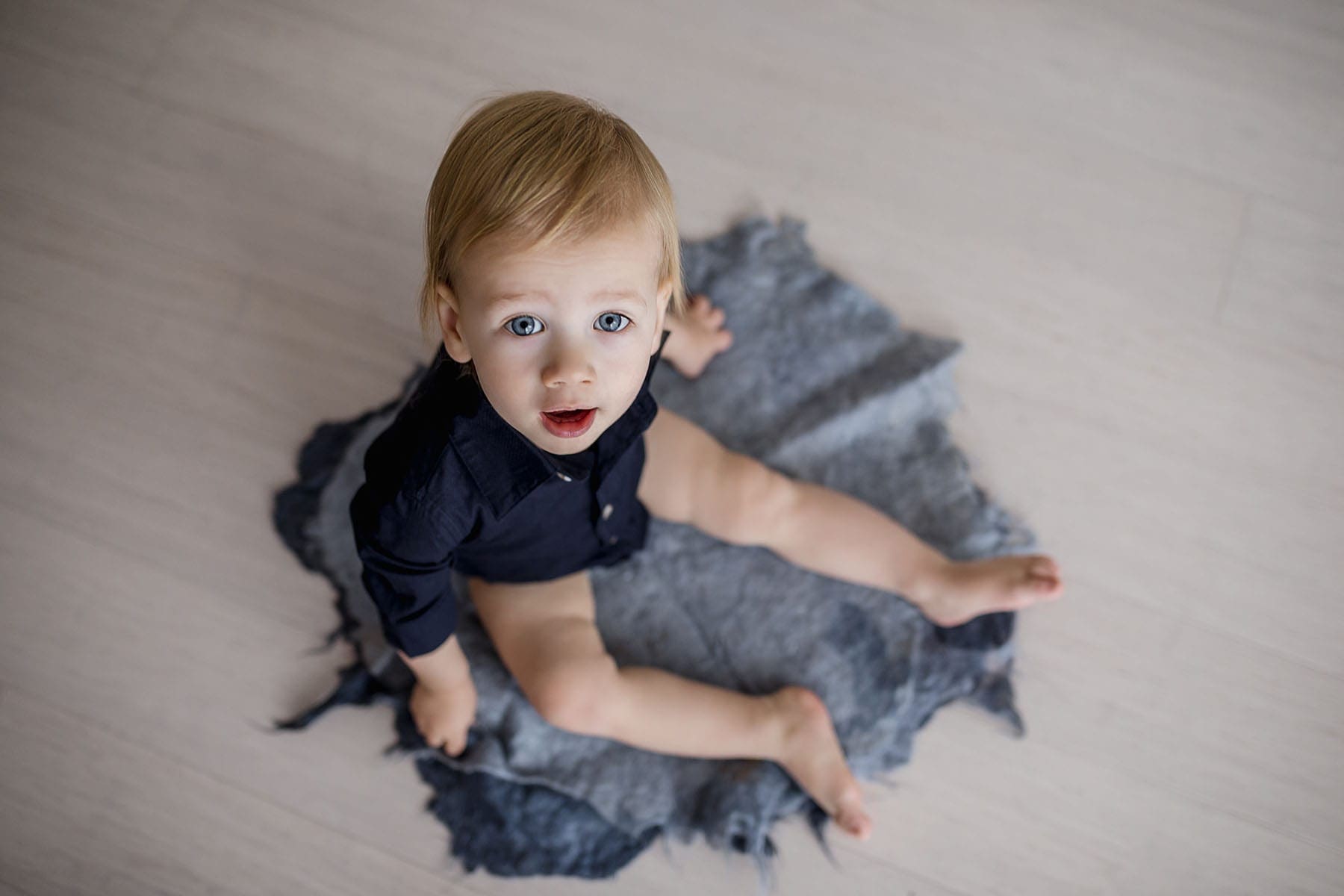Sydney-Studio-Baby-Photographer-Elysium-Photography-Matthew-8 A baby boy sits on a blue matt and gazes at the camera with his blue eyes