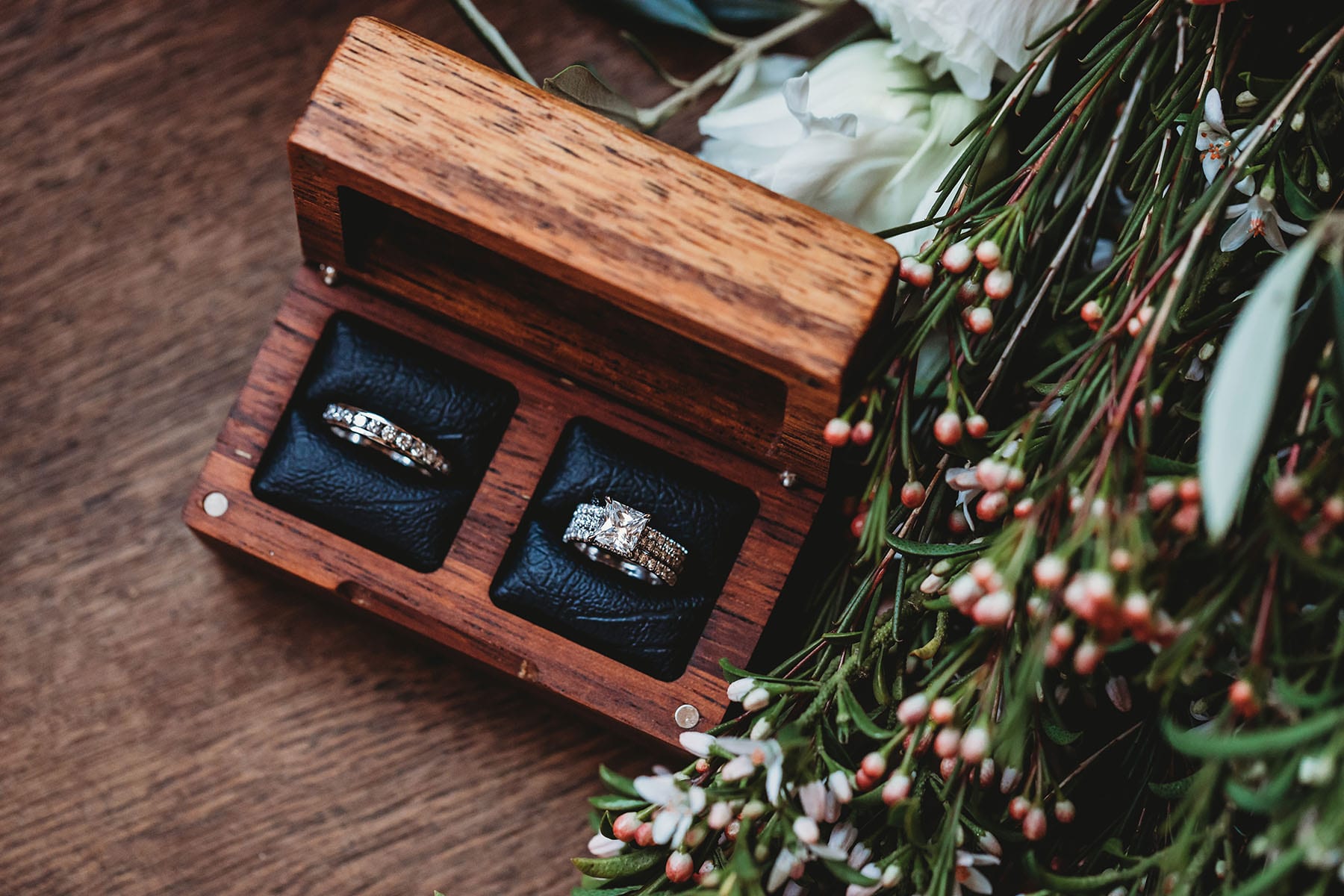 Details, wedding rings in a timber box sitting in the bridal bouquet
