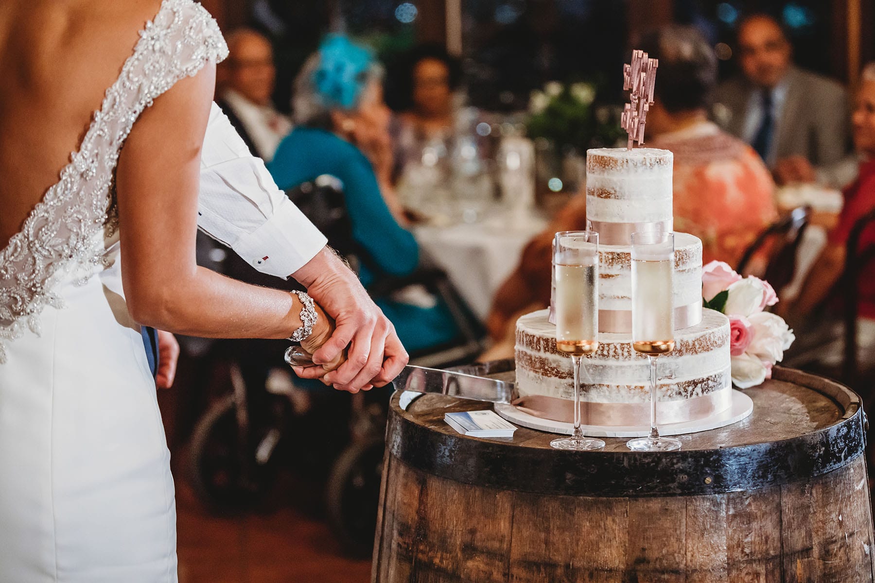 Close up photograph of a couple's hands cutting their wedding cake