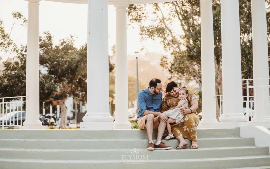 Family Photographer - Parents hug their daughter as they sit on the Balmoral Rotunda steps