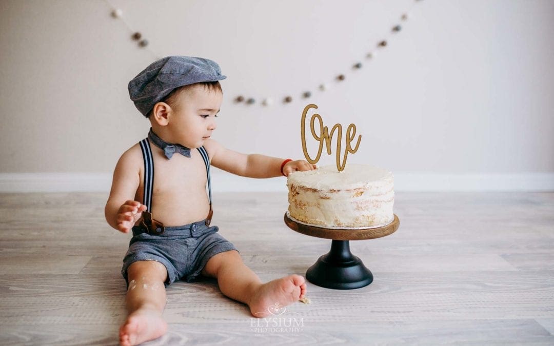 Little boy touching his first birthday cake before smashing it