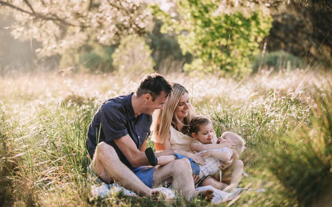 Family Photographer - A family sit cuddling in a grassy field