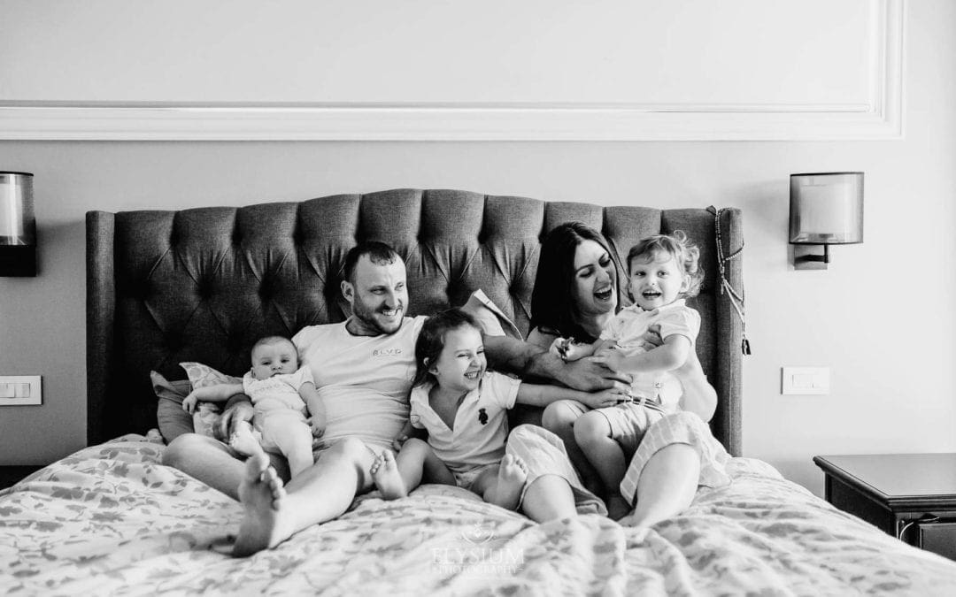 in home session, family sits on the bed and laughs