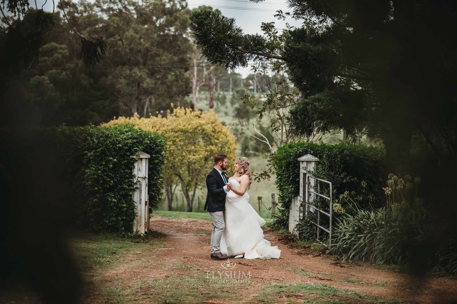 Gledswood Wedding Photo - bride and groom embrace standing on the homestead driveway