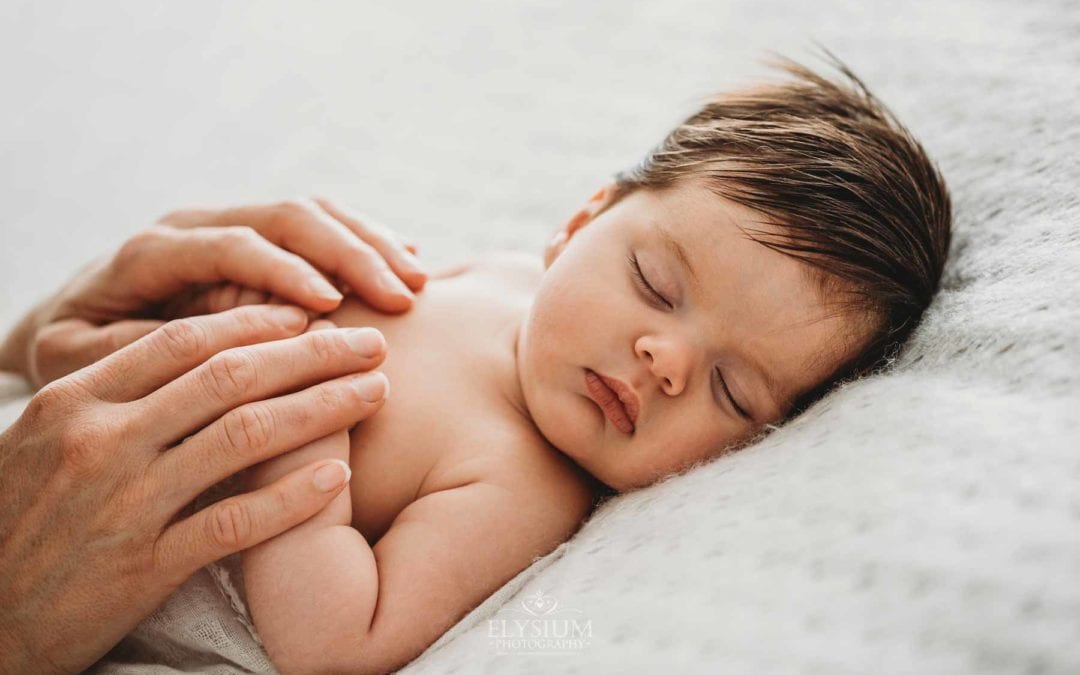 Baby Photography - a mother holds her sleeping newborn's hands