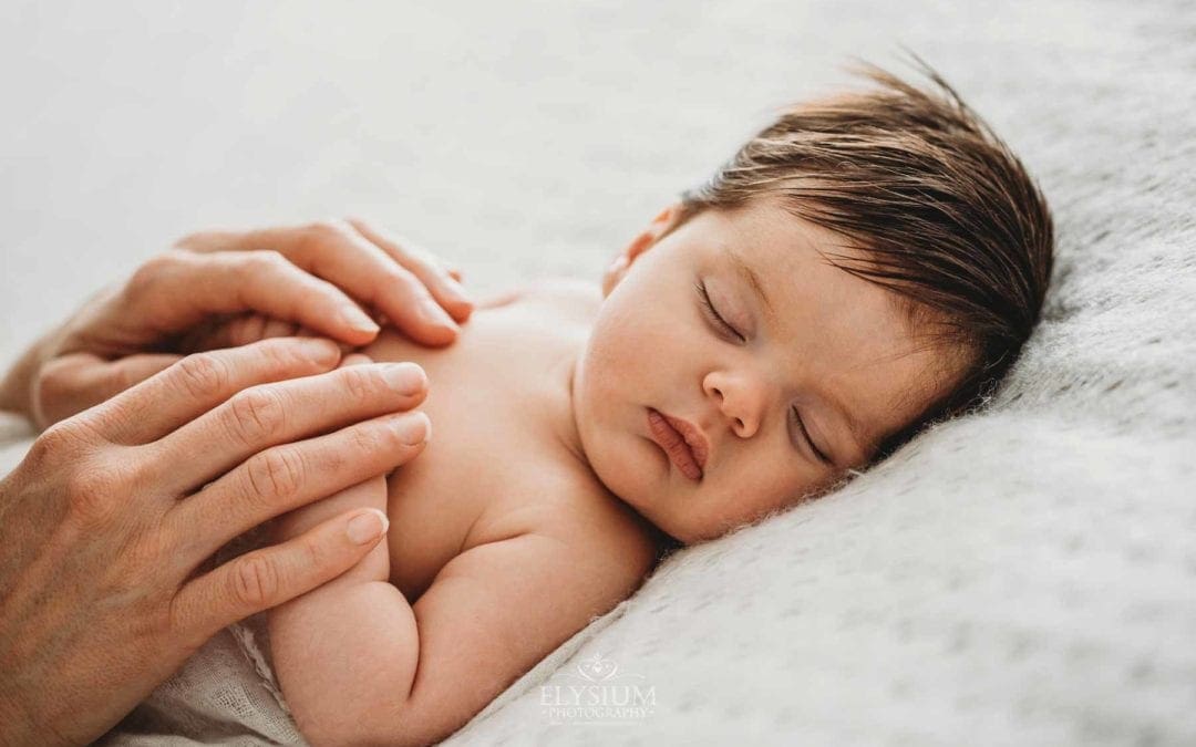 Baby Photography - a mother holds her sleeping newborn's hands