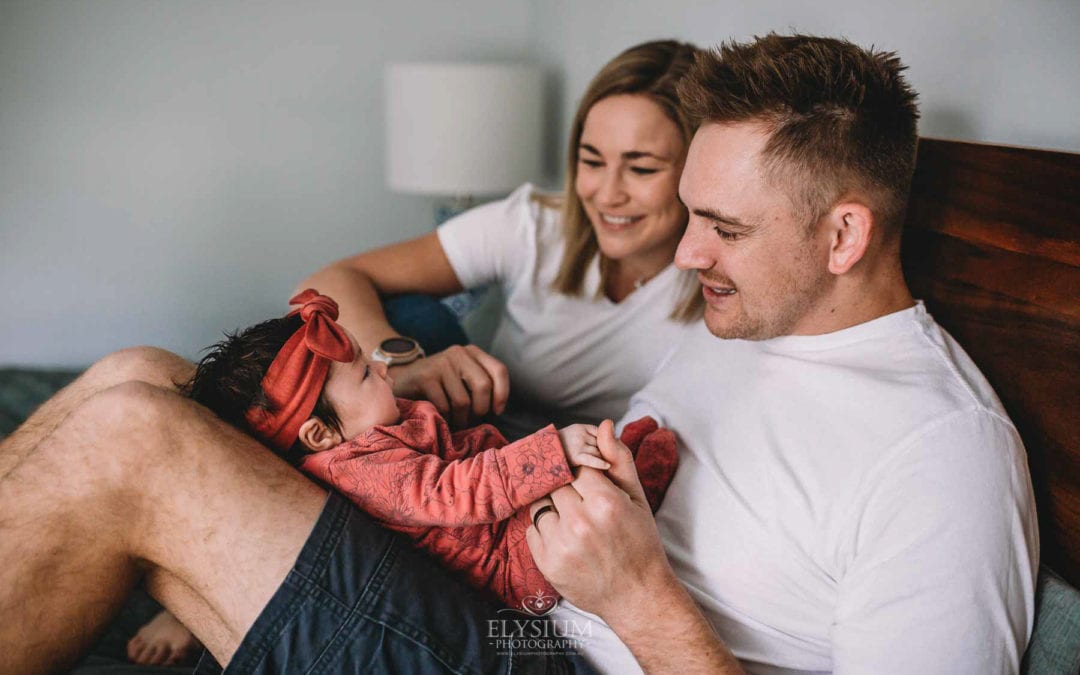 Newborn Photography - parents cradle their baby in their laps