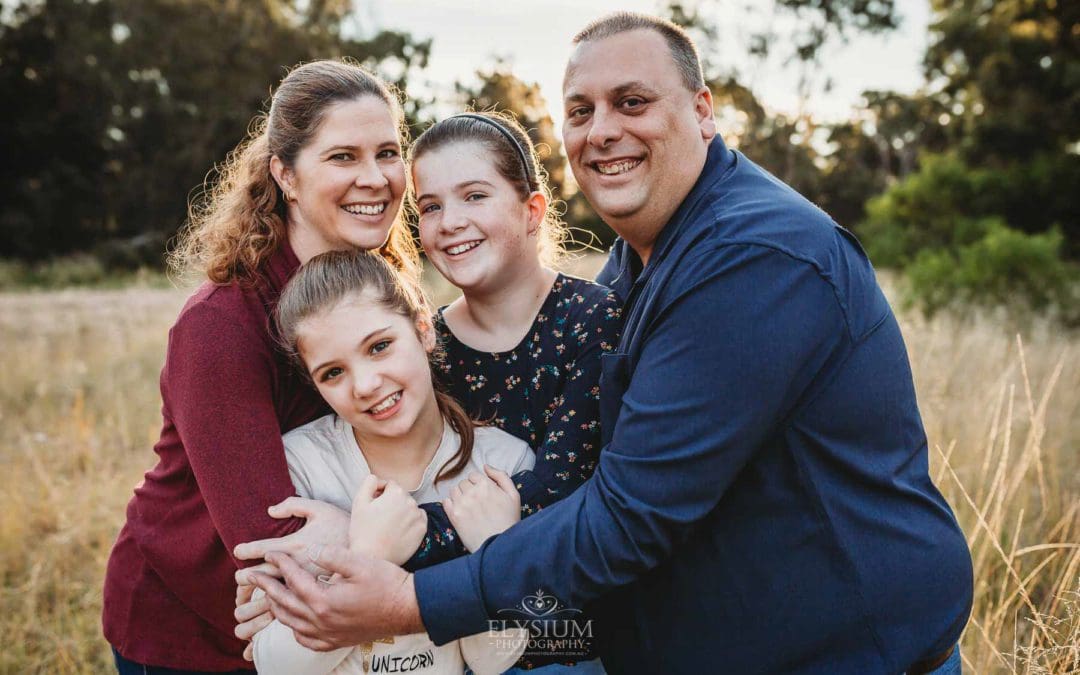 A family cuddle together standing in long grass