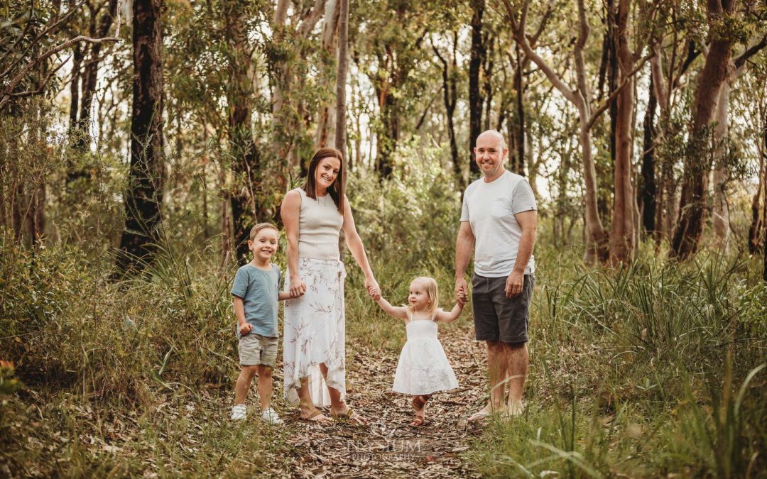 A family stand on a bush path holding hands