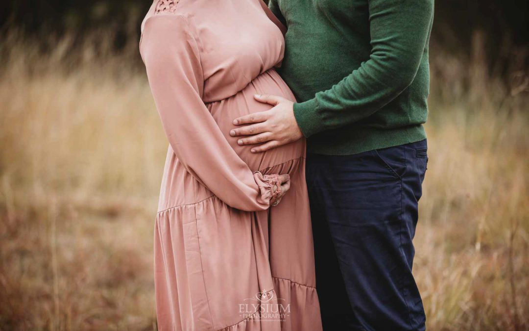 A man holds his pregnant wife's belly