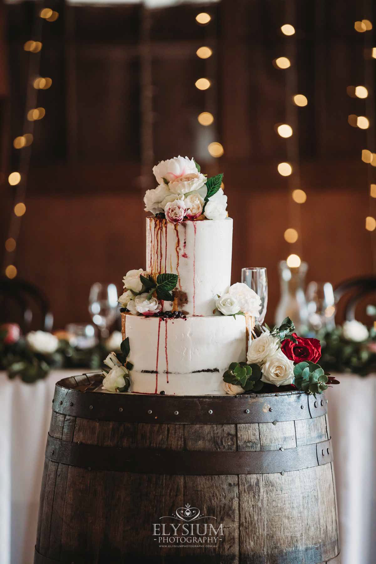 Gledswood Wedding - wedding cake sits on a wine barrel in the reception venue