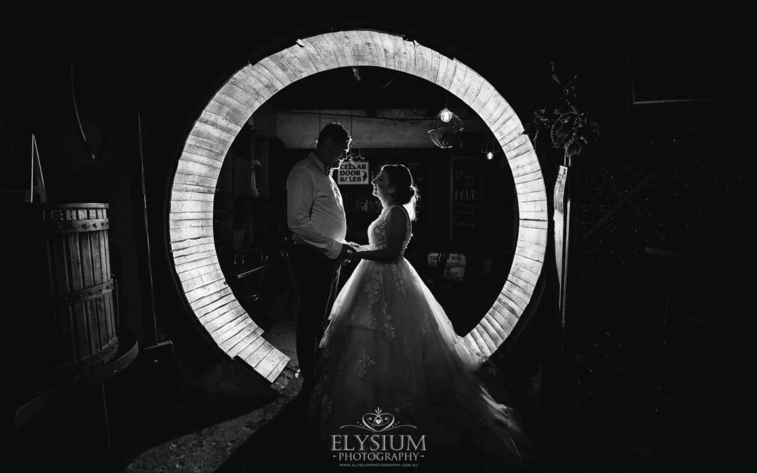 Newlyweds stand in a circular doorway with a bright light behind them at Gledswood
