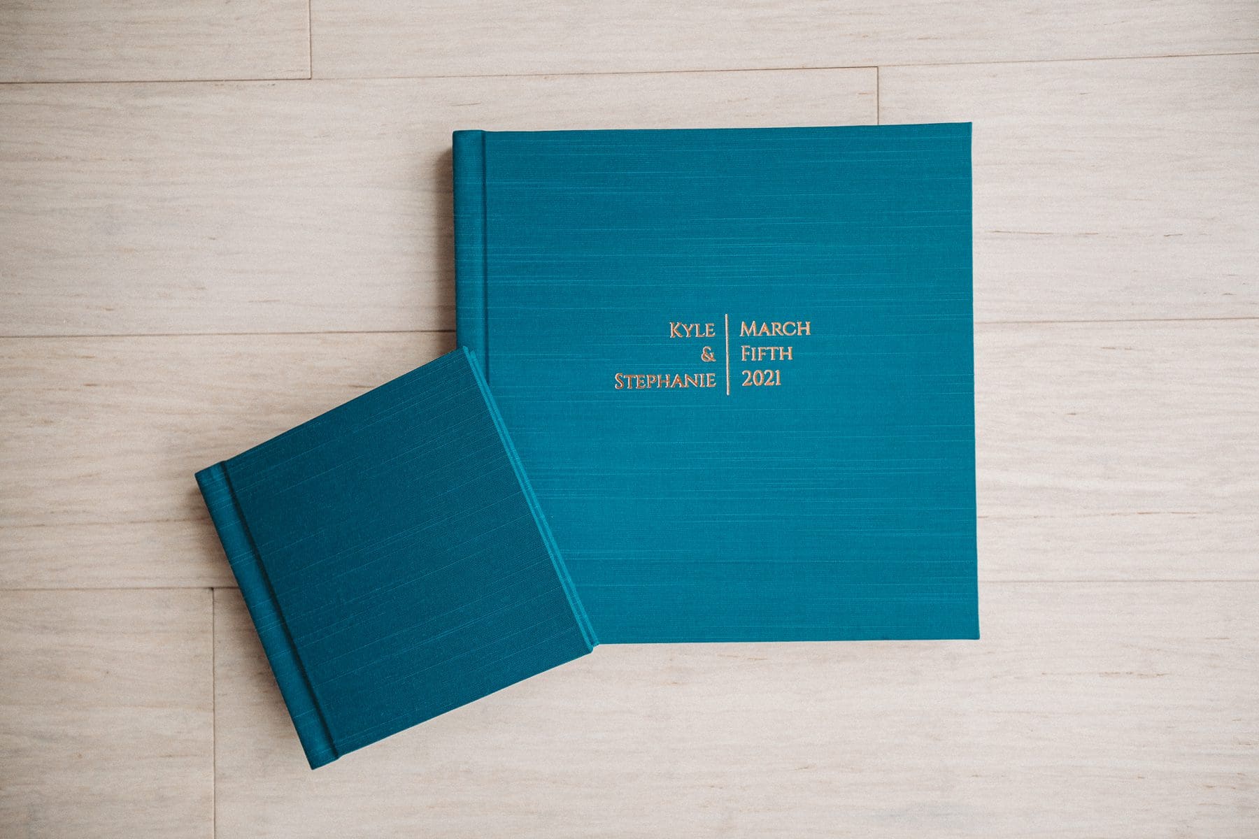 Wedding photo album covered in teal material with gold foil embossing