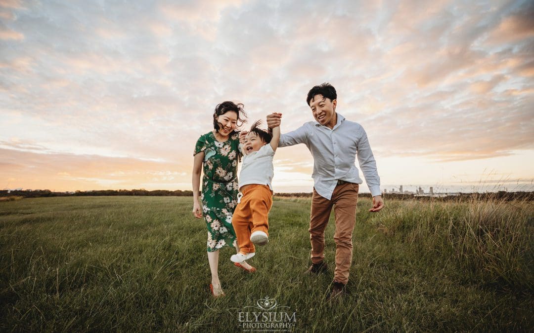 A family hold their baby's hands and swing him as they walk