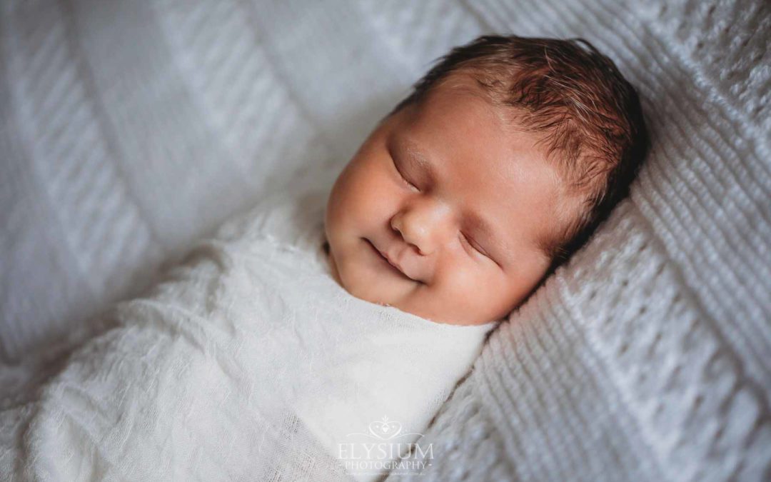 Newborn Photography: a baby boy lays wrapped on a white blanket