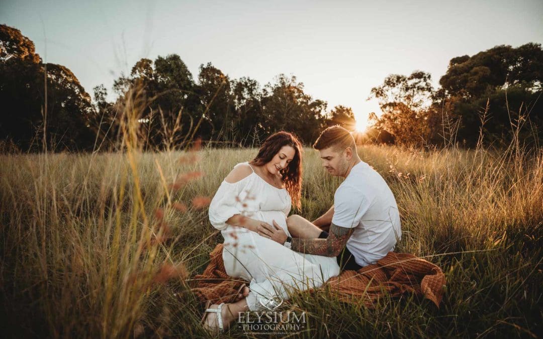 Outdoor Session - a couple sit on a blanket in long grass at sunset