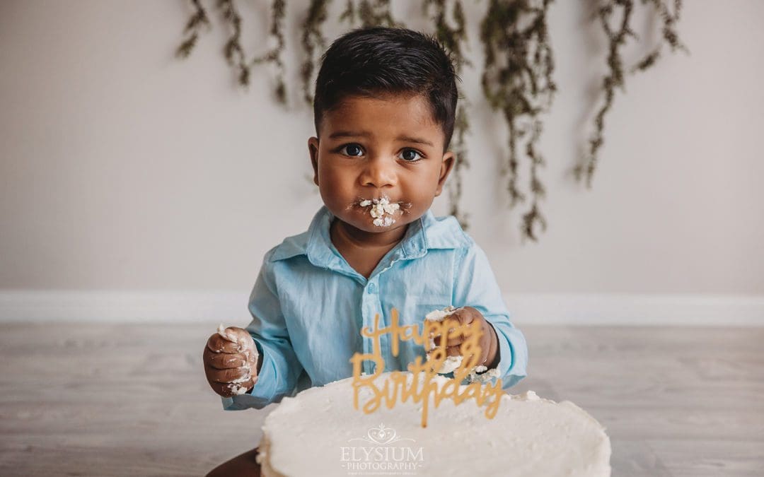 A baby boy plays with icing during his messy cake smash session