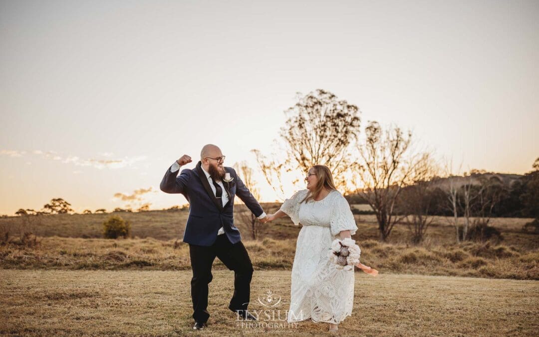 A bride and groom pump their fists in the air after their wedding at sunset