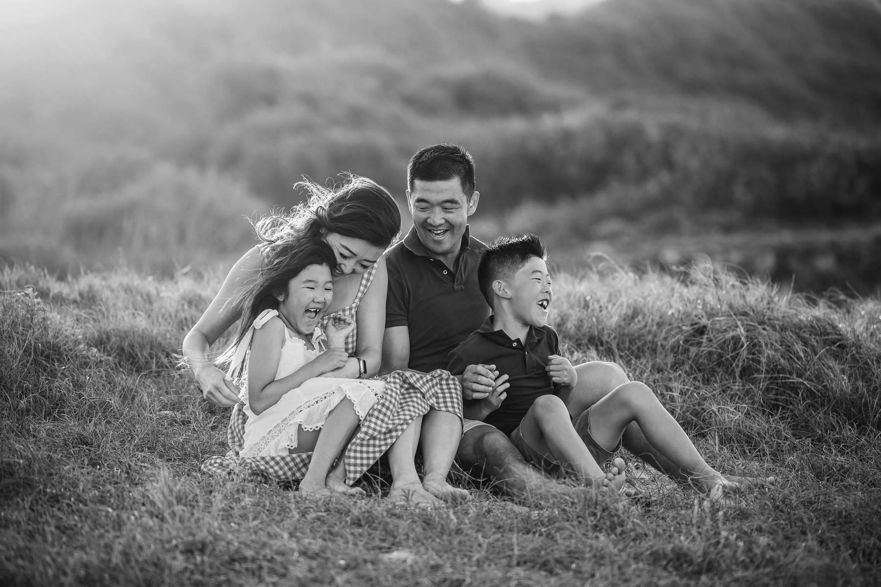 A family photo session with kids and their parents sitting on a Sydney beach at sunset