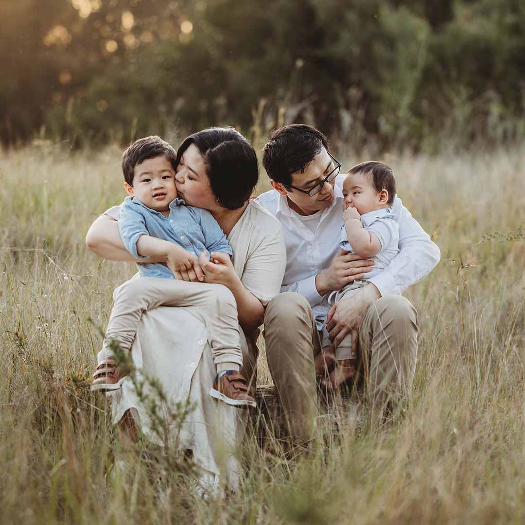 Elysium-Photography-Sydney-Family-Photographer-Xu-78 A little girl lays on a white fur rug cuddling her newborn baby sister