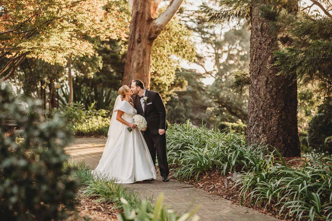 Elysium-Photography-Sydney-Wedding-Photographer-Wilson-732 Gledswood Wedding - A groom cuddles his bride in a dimly lit room in front of a small window