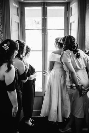 Sydney Wedding Photographer - bridal party look out a window to the ceremony