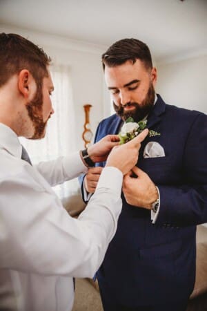 Sydney Wedding Photographer - groomsman attaches the grooms buttonhole flower