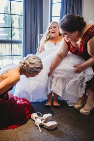 Gledswood Wedding - bridesmaids help the bride with her shoes