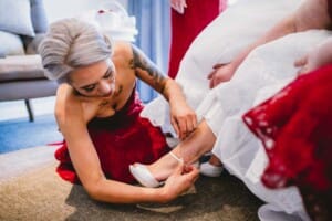 Gledswood Wedding - bridesmaids help the bride with her shoes