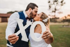 Gledswood Wedding - bride and groom hold large X and O signs