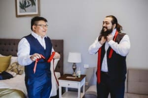 Gledswood Wedding - groomsman does up his tie during prep
