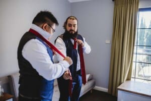 Gledswood Wedding - groomsman does up his tie during groom prep