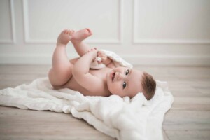 9 month old baby boy rolling about on his blanket