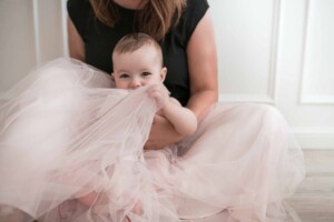 Baby boy playing peekaboo under mum's skirt