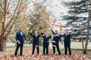 Groomsmen trowing around the fallen leaves