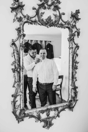 Groomsman helping the groom with his tie