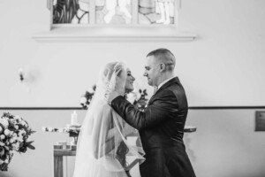 The groom lifts his brides veil for their first kiss