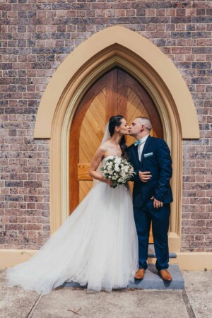 Bride and groom share a kiss outside the church
