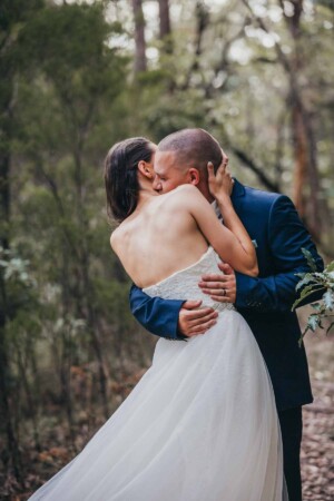 A groom kisses his bride on the neck