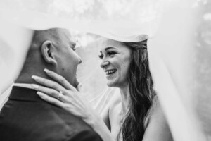 A bride and groom laughing under her veil