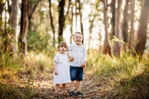 Siblings holding hands in the sunlit bushland